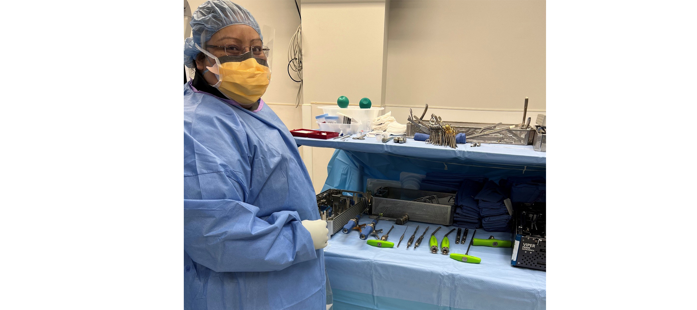 Elizabeth wearing. surgical gown and surgical instruments on a table 