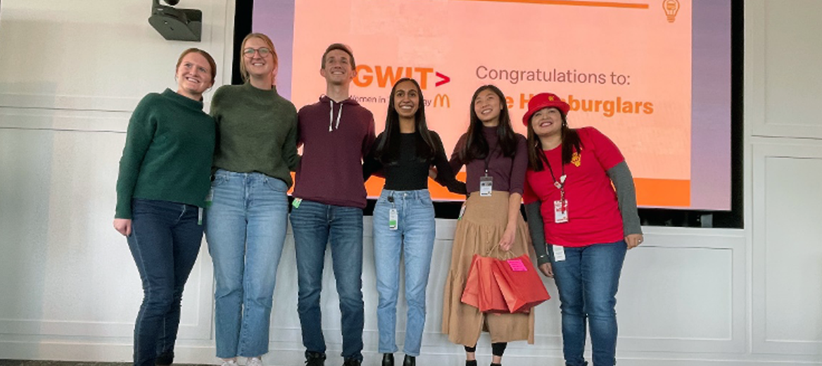 The group posing in front of a presentation