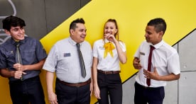 Four McDonald's employees smiling and laughing outside a restaurant