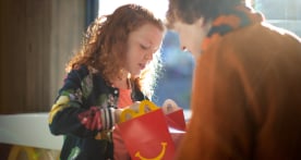 Father holding a Happy Meal box for daughter to open
