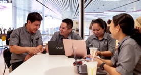 Four McDonald's employees working together at a table with laptops