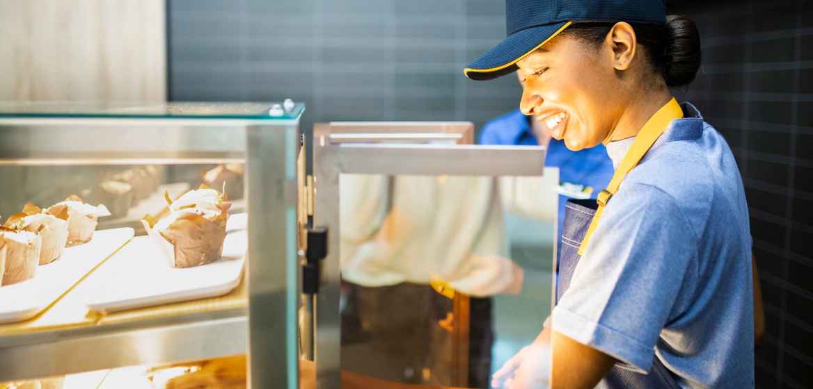A McDonald's employee looking into a glass display containing food items