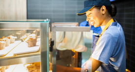 A McDonald's employee looking into a glass display containing food items